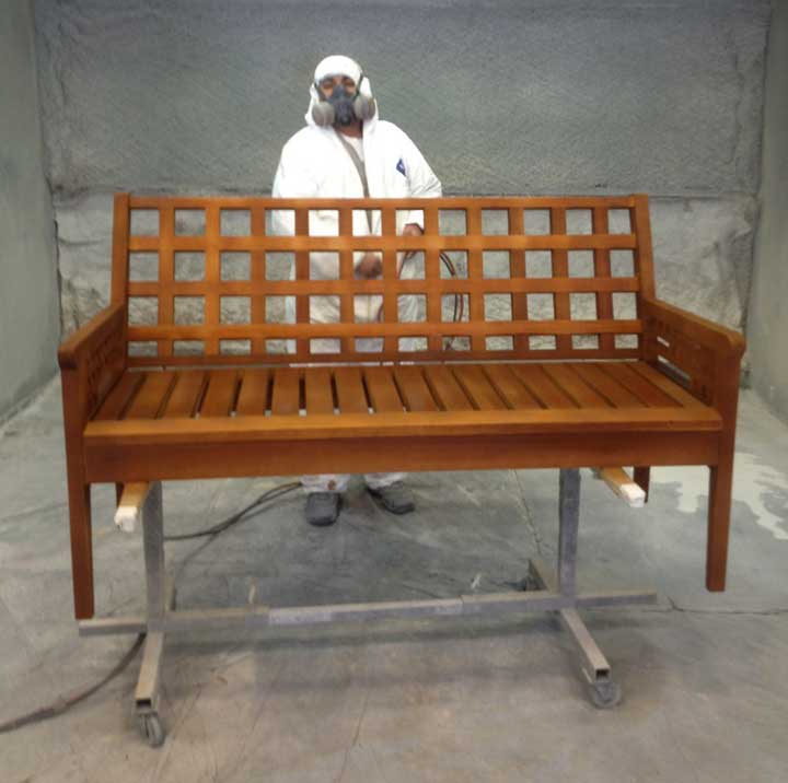 spraying WoodRX finish on an outdoor bench